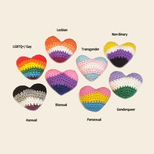 May include: Nine crocheted hearts, each representing a different sexual orientation or gender identity. The hearts are arranged in a semi-circle, with the text "LGBTQ+/ Gay", "Lesbian", "Bisexual", "Asexual", "Transgender", "Non-Binary", "Genderqueer", "Pansexual" and "Asexual" written below each heart.