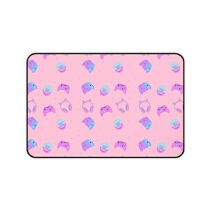 Puede incluir: Alfombrilla de ratón rectangular rosa con borde negro. Presenta un patrón repetido de mandos de videojuegos, auriculares y consolas en tonos morados, azules y turquesas. Pequeños corazones rosas están dispersos por el diseño.