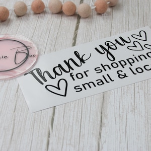 May include: A rectangular white card with black text that reads Thank you for shopping small & local with three heart icons, alongside a circular pink acrylic disc featuring the black text Bessie Boo inside a circular border.