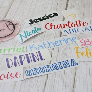 May include: A collection of colourful vinyl stickers with various names, including Jessica, Ivy, Nicole, Charlotte, Abigail, Harriet, Katherine, Bessie, Daphne, Felicity, Eloise, and Georgina.