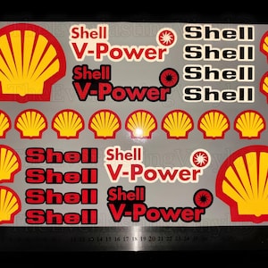 May include: Sheet of Shell and V-Power stickers. The stickers feature the Shell logo, a yellow and red scallop shell, and the text "Shell" and "V-Power" in red and white. The stickers are on a gray background.
