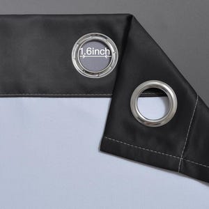 Puede incluir: Primer plano de un panel de cortina negro con una arandela plateada. La abertura de la arandela tiene 4,1 cm de di&aacute;metro. La cortina tiene un forro blanco y un fondo gris.