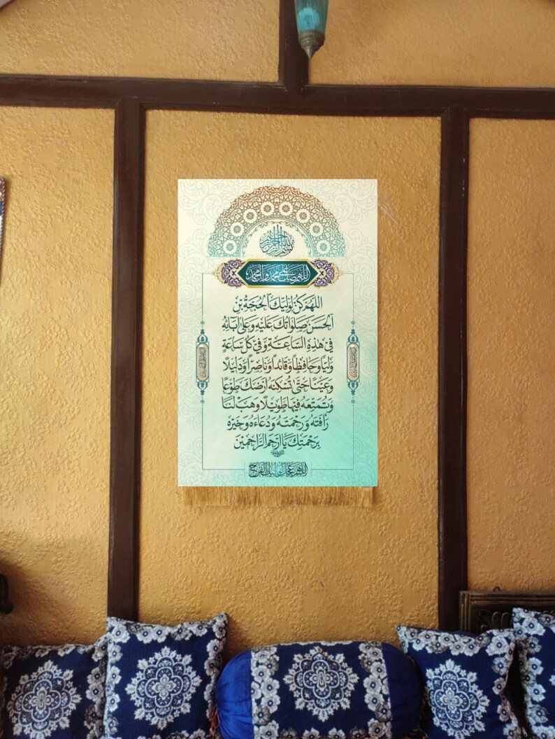 May include: A framed Islamic calligraphy print with a blue and green color scheme. The print features Arabic text and a decorative border. The print is hanging on a yellow wall with a brown wooden frame.