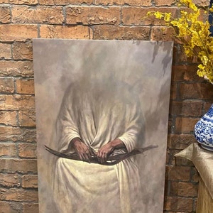 May include: A painting depicting a figure in a white robe seated with their hands clasped in their lap. The background is a muted grey with a hazy effect.