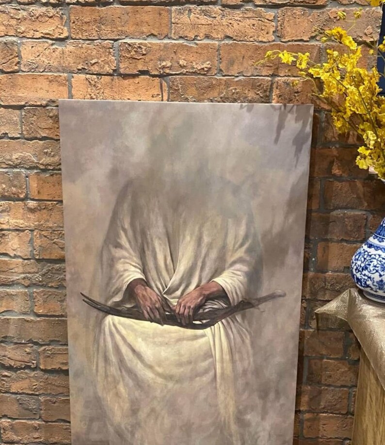 May include: A painting depicting a figure in a white robe seated with their hands clasped in their lap. The background is a muted grey with a hazy effect.