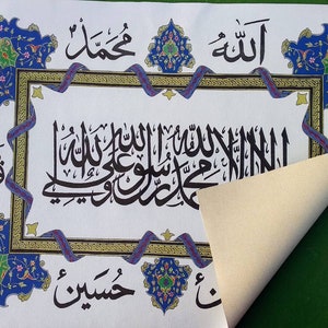 May include: A white canvas with intricate blue and gold calligraphy in Arabic script. The text includes the words "Allah" and "Muhammad". The canvas is framed with a decorative border of blue and gold floral designs.