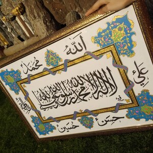 May include: A framed piece of Islamic calligraphy art with intricate floral designs in blue, green, and gold. The calligraphy is in Arabic and reads "Allah" and "Muhammad".