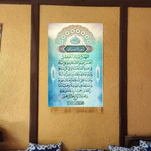 May include: A blue and gold Islamic calligraphy wall hanging with an intricate design and Arabic text. The text reads "Allahumma kun li waliyyika al-Hujjah ibn al-Hasan, salawatuk alaihi wa ala abaihi, fi hadhihi al-sa'ah wa fi kulli sa'ah, waliyyan wa hafizhan wa qa'idan wa nasiran wa dalilan wa 'ainan hatta tuskinahu ardaka tau'an wa tumatti'ahu fiha tawilan wa hab lana rafatahu wa rahmatahu wa du'a'ahu wa khai rahu bi rahmatika ya arhamar rahimin."
