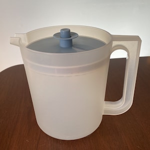 May include: A translucent plastic pitcher with a light blue lid and handle. The pitcher has a wide opening and a spout for easy pouring. The handle is sturdy and comfortable to grip. The pitcher is designed for serving cold beverages.