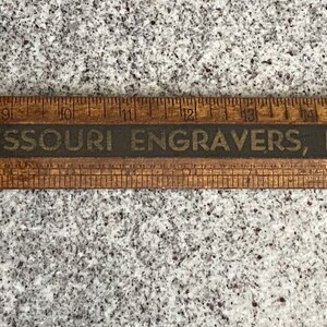 May include: A wooden ruler with a black stripe that reads "Missouri Engravers, Inc. - 7th Street - Kansas City, Mo."
