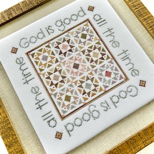 Puede incluir: Un bordado de punto de cruz enmarcado con un diseño de patchwork en tonos marrones, verdes y rosas. El texto "God is good all the time, all the time God is good" está bordado alrededor del diseño de patchwork.