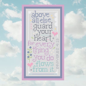 May include: Cross-stitch artwork with a sky blue and white background. The framed piece features the text "above all else guard your heart for everything you do flows from it." The text is in various colors, including blue, pink, and green.