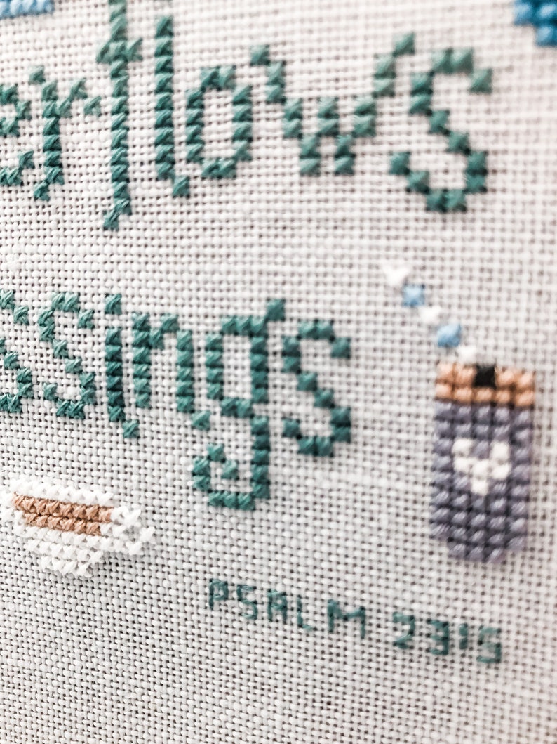 May include: Cross-stitch embroidery with teal blue thread, depicting a cup of coffee and the words "Fellows Greetings" with the text "PSALM 23:6" below.
