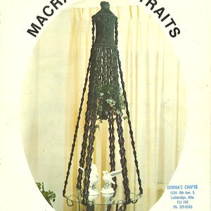 May include: A black macrame plant hanger with a glass shelf and two white porcelain birds. The hanger is hanging from a ceiling in a room with white curtains. The title "Sir Lancelot" is printed below the image. The text "Donna's Crafts" is printed in the lower right corner of the image.