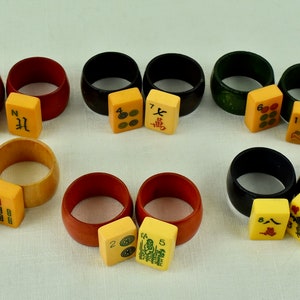 May include: Set of 10 wooden napkin rings with matching mahjong tiles. The rings are in various colors, including red, black, green, and natural wood. The tiles feature Chinese characters and numbers.