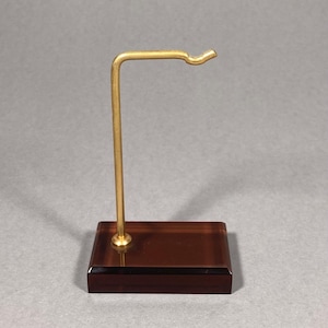 May include: A gold metal display stand with a curved arm and a dark brown rectangular base.