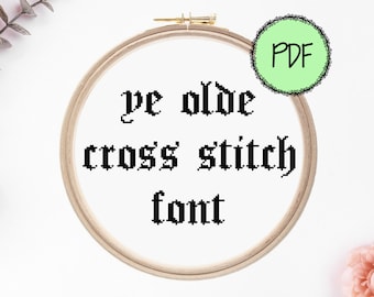 May include: A wooden embroidery hoop with white fabric inside. The fabric has black text that reads "ye olde cross' stitch font". A green circle with a white outline and the word "PDF" inside is in the upper right corner of the image.