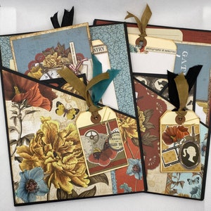 Op de afbeelding: Een scrapbook met een zwarte omslag en verschillende gepatroneerde papieren en versieringen. De scrapbook heeft een zakje aan de voorkant met een label waarop "Gather" staat en een label waarop "Photography & Memories" staat.