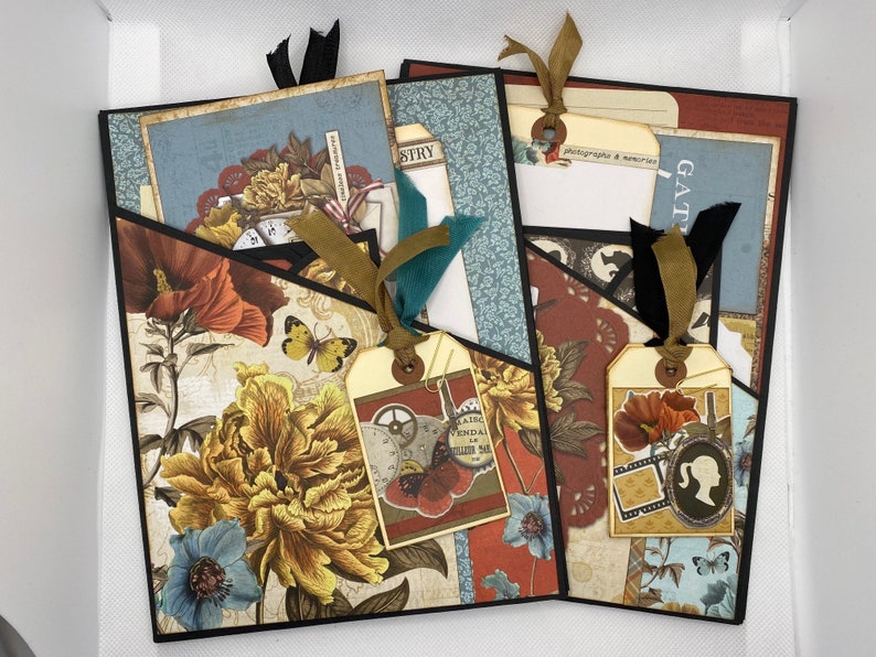 Op de afbeelding: Een scrapbook met een zwarte omslag en verschillende gepatroneerde papieren en versieringen. De scrapbook heeft een zakje aan de voorkant met een label waarop "Gather" staat en een label waarop "Photography & Memories" staat.