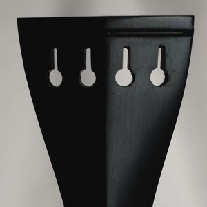 以下が含まれることがあります： 3つのチューニングペグが付いた黒いバイオリンのテールピース。テールピースは木でできており、滑らかで磨かれた仕上げになっています。