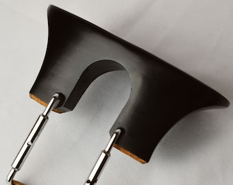 May include: A black wooden violin shoulder rest with adjustable metal supports. The shoulder rest has a cork pad on the bottom.
