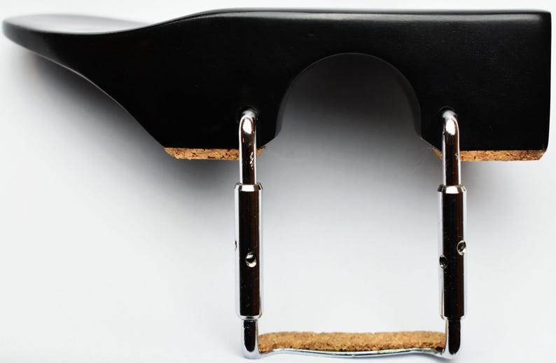 May include: A black violin shoulder rest with a curved design. It features a wooden frame with a cork pad and adjustable metal brackets. The shoulder rest is designed to provide comfort and support for violin players.