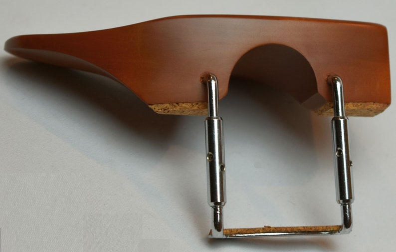 May include: A brown wooden violin shoulder rest with a curved design. It features a cork base and adjustable metal supports. The shoulder rest is designed to provide comfort and support for violin players.