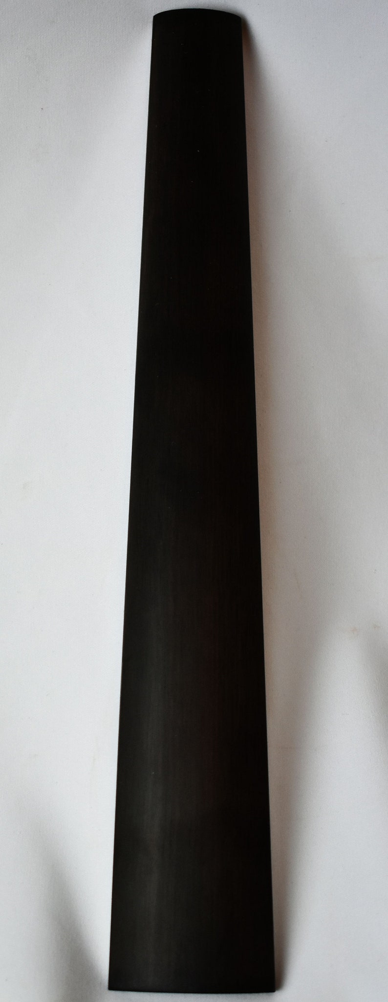 May include: A black guitar neck blank, ready to be shaped and finished.