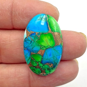 May include: An oval-shaped gemstone with a mosaic of colors. The stone features vibrant blues, greens, and copper-colored matrix. The polished surface reflects light, highlighting the intricate patterns and textures within the stone. A unique and eye-catching piece.