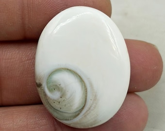 May include: Oval-shaped white gemstone with a swirling pattern of green and brown hues. The polished surface reflects light, highlighting the natural variations in the stone. This gemstone is suitable for jewelry making.