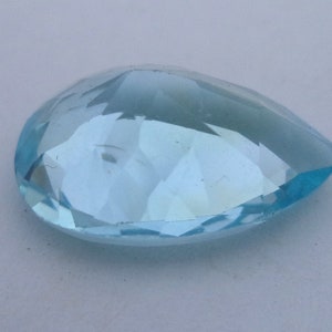 May include: A light blue pear-shaped gemstone with a faceted cut.