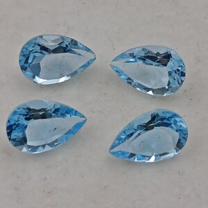May include: Four teardrop-shaped, light blue gemstones. The gemstones are faceted and have a pearlescent sheen.