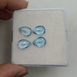 May include: Four teardrop-shaped, light blue gemstones in a white box.