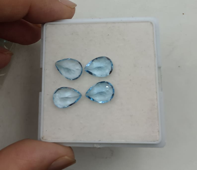 May include: Four teardrop-shaped, light blue gemstones in a white box.