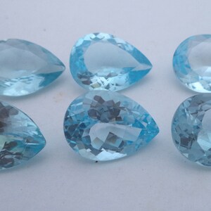 May include: Six pear-shaped, light blue gemstones. The gemstones are faceted and have a clear, glassy appearance.