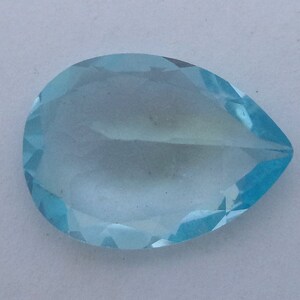 May include: A light blue teardrop-shaped gemstone with a faceted cut.