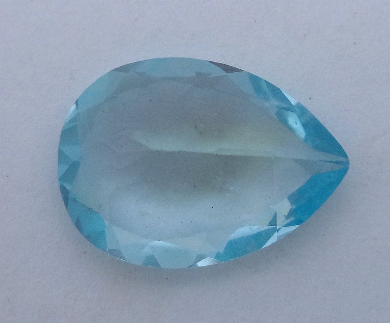 May include: A light blue teardrop-shaped gemstone with a faceted cut.