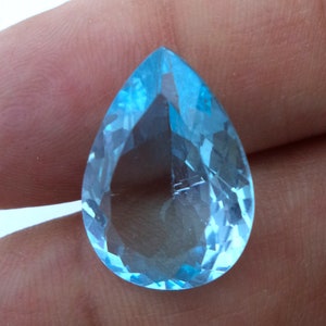 May include: A teardrop-shaped, faceted gemstone with a light blue color.
