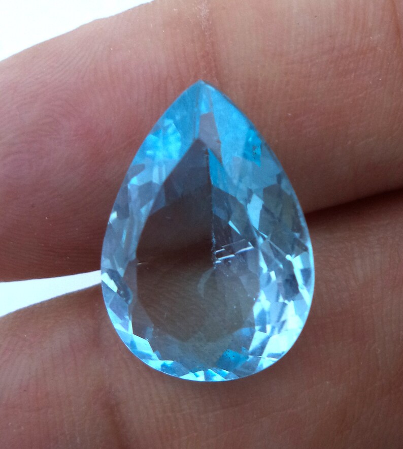 May include: A teardrop-shaped, faceted gemstone with a light blue color.