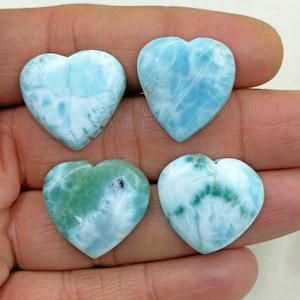 Peut inclure: Quatre pierres précieuses en forme de cœur dans des tons de bleu et de vert. Les pierres ont un aspect marbré avec des motifs et des textures variés. Les pierres précieuses sont tenues dans une main, mettant en valeur leurs surfaces polies et leurs variations de couleurs uniques.