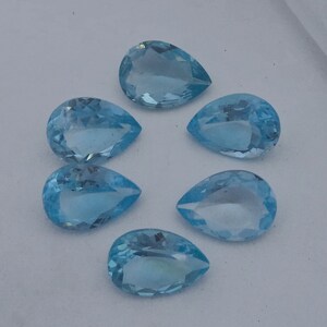 May include: Six pear-shaped, light blue gemstones. The gemstones are faceted and have a smooth, polished finish.