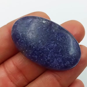 K&ouml;nnte beinhalten: Ein glatter, ovaler blauer Edelstein mit einer funkelnden, strukturierten Oberfl&auml;che. Der Stein hat eine hellblaue Farbe mit dunkleren blauen Flecken.