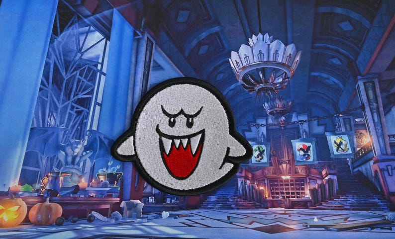 Puede incluir: Un fantasma blanco con una boca roja y dientes afilados, un personaje popular de videojuego, est&aacute; bordado en un parche de tela.