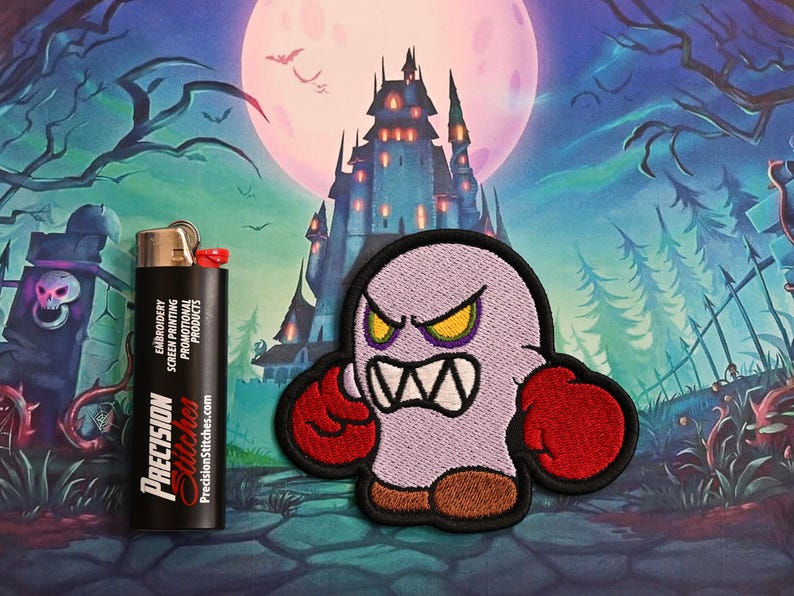 May include: Embroidered patch of an angry cartoon ghost with red boxing gloves and brown feet. A black lighter with "Precision Stitches" text is next to the patch. The background shows a spooky castle and a full moon.