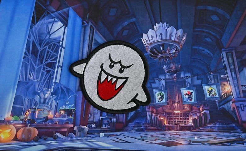 Puede incluir: Un fantasma blanco con una sonrisa roja y dientes, bordado en un parche de tela. El fantasma est&aacute; en una habitaci&oacute;n oscura de estilo g&oacute;tico con una l&aacute;mpara de ara&ntilde;a y otros elementos decorativos.