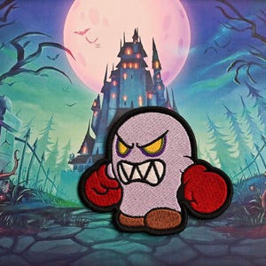 May include: Embroidered patch of a cartoon ghost with an angry expression. The ghost is light purple with red boxing gloves and brown shoes. The background shows a spooky scene with a castle, full moon, and graveyard.