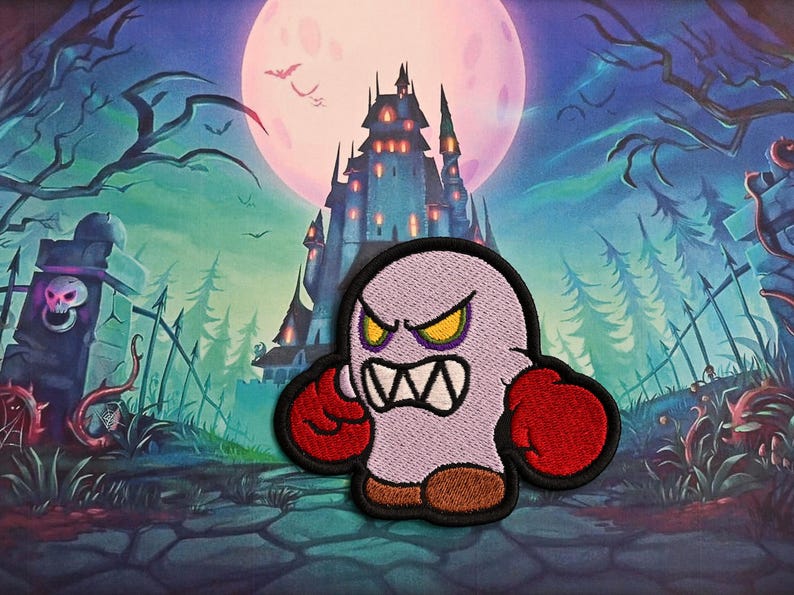 May include: Embroidered patch of a cartoon ghost with an angry expression. The ghost is light purple with red boxing gloves and brown shoes. The background shows a spooky scene with a castle, full moon, and graveyard.