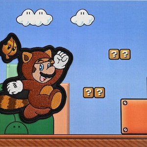 May include: Embroidered patch featuring a cartoon character in a tanuki suit, jumping in front of a blue sky background with white clouds, question mark blocks, and colorful platforms. The patch has a black border.