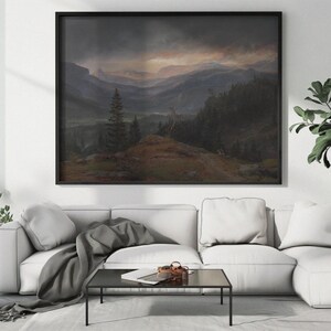 May include: A framed landscape painting depicting a mountain range with a dark, stormy sky. The painting is in a black frame and is hanging on a white wall above a white couch.