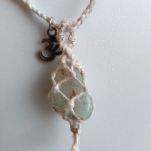 May include: A white macrame necklace with a green stone pendant and a silver Om symbol charm.
